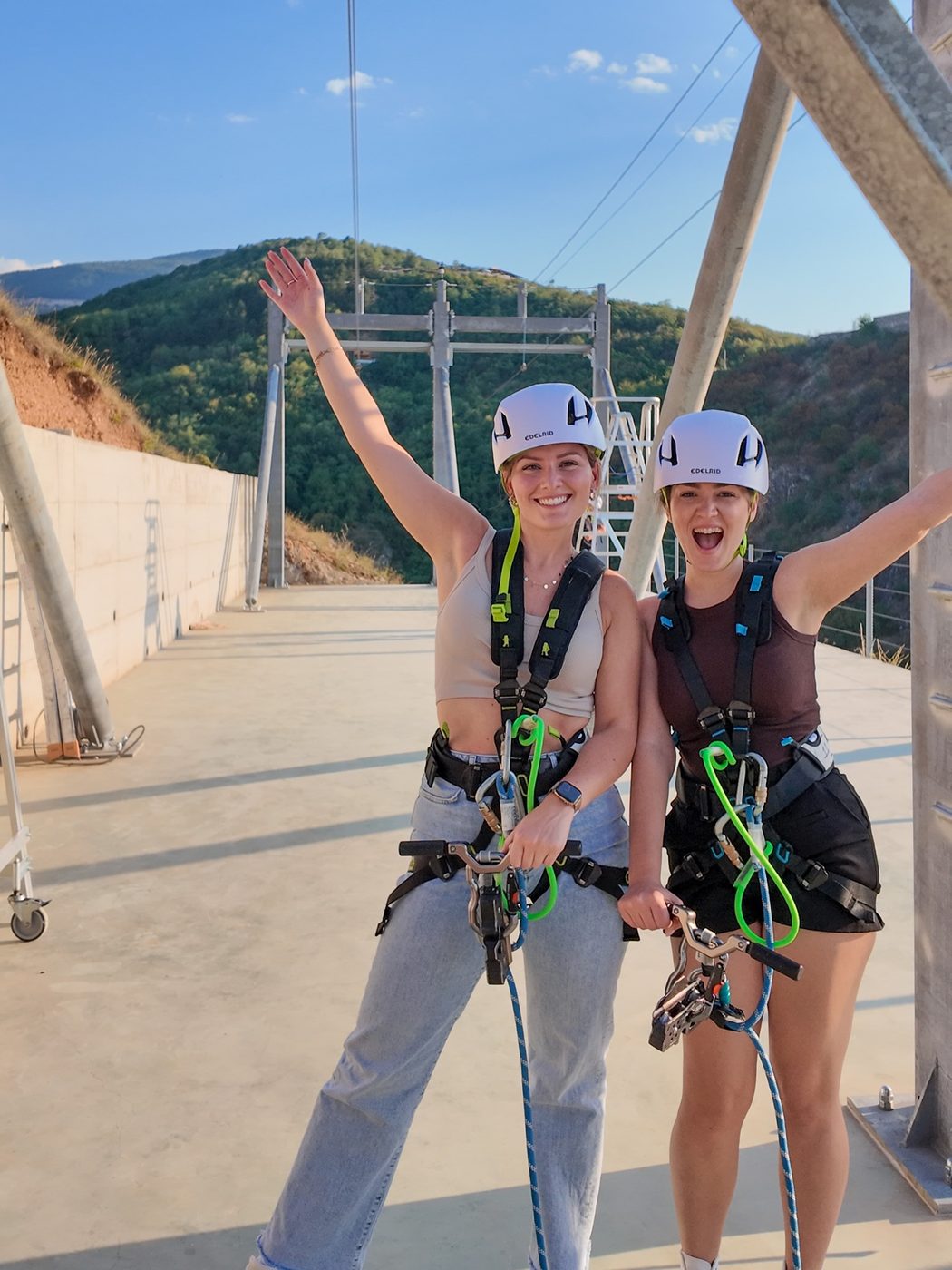 Two friends in helmets and harnesses cheer on the landing platform