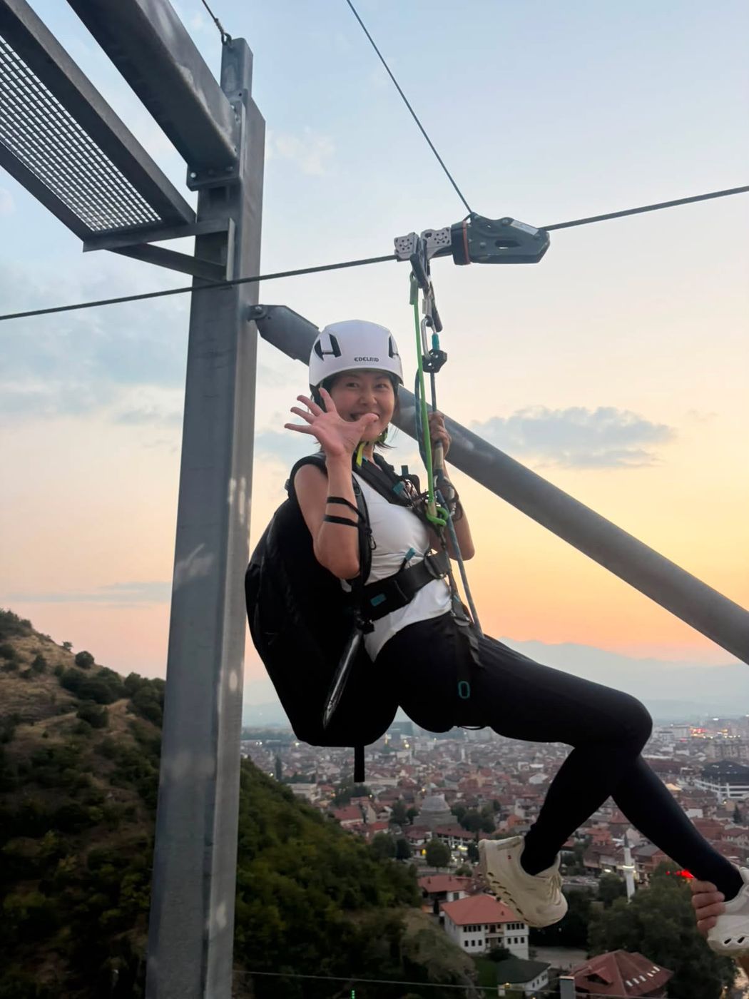 A rider waves from the cable at sunset, Prizren below